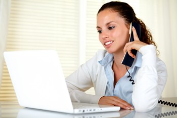 Woman talking on the phone while looking at her laptop